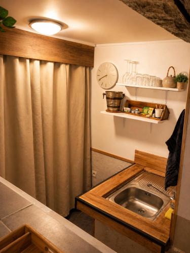 a kitchen with a sink and a clock on the wall at Suite spa Romantique avec piscine privée cosy clim in Coligny