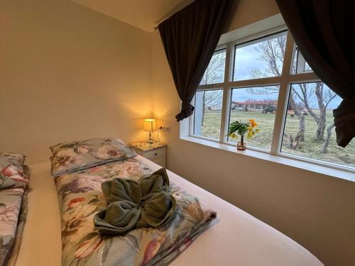 a bedroom with a bed with a flower blanket and a window at Hrutafell Guesthouse in Hvolsvöllur