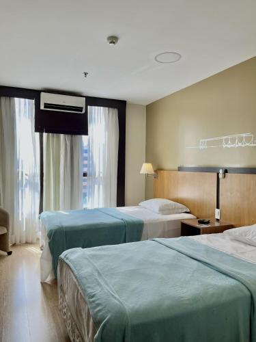 a hotel room with two beds and a window at Flat 609 - Comfort Hotel Taguatinga - Particular in Brasília