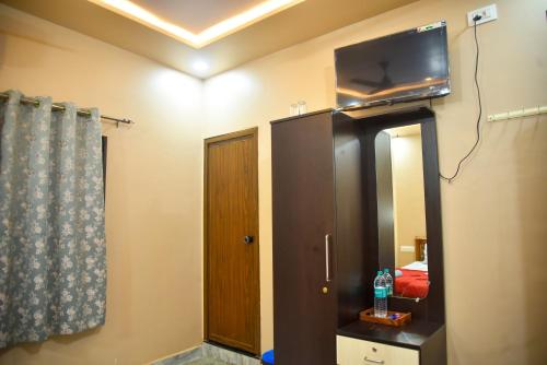 a bathroom with a mirror and a tv on the wall at JFZ Homestay in Kāsarkod