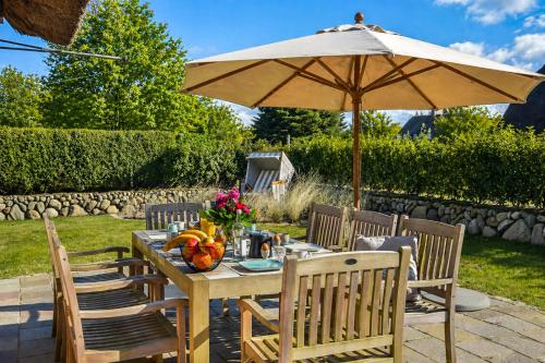 a wooden table with an umbrella and chairs at Haus Lang Libben in Archsum