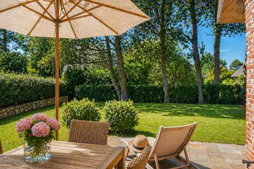 a wooden table with an umbrella and chairs at Haus Goed Libben in Archsum