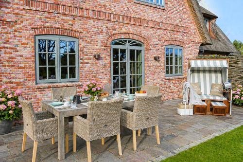 a patio with a table and chairs in front of a brick building at Haus Goed Libben in Archsum
