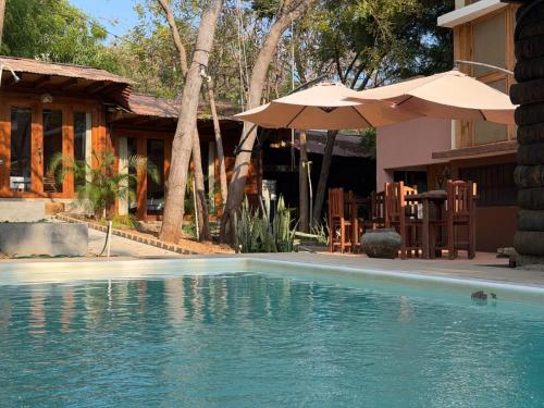 a swimming pool with an umbrella and a house at Straw hat suites La punta in Santa María Colotepec