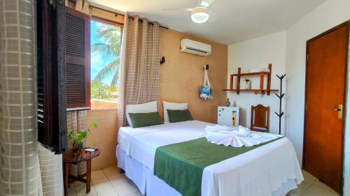 a bedroom with a bed in a room with a window at Casa Mandacaru Pousada in Cumbuco