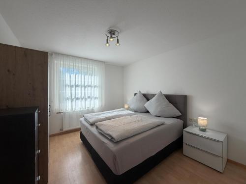 a white bedroom with a bed and a window at Seegarten Apartment 4 in Hagnau