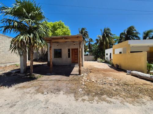ein kleines Haus mit einer Palme neben einem Gebäude in der Unterkunft Casa Haema in El Cuyo