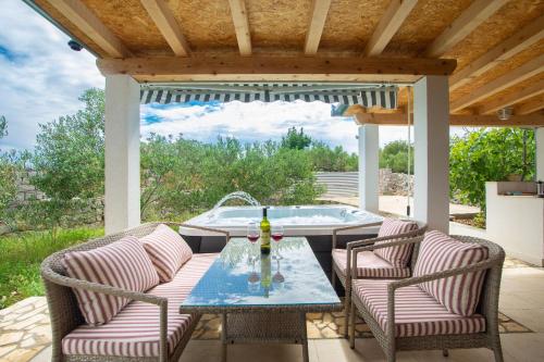 a patio with a table and chairs and a tub at House Lila Jacuzzy in Drvenik Mali