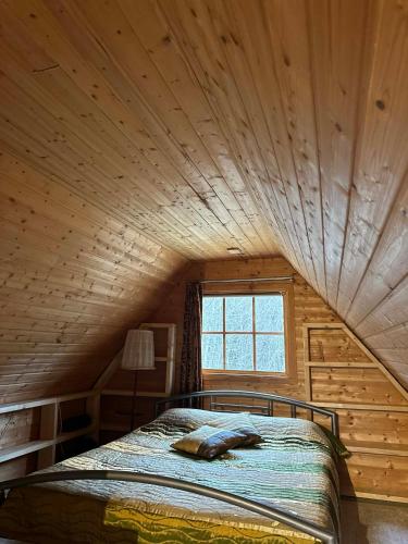 a bed in a room with a wooden ceiling at Tammetalu puhkemaja in Nõmme