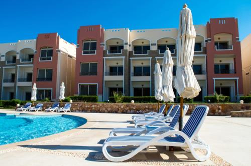 a resort with chairs and umbrellas and a swimming pool at شاليه in Marsa Alam