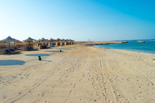 a beach with umbrellas and chairs and the ocean at شاليه in Marsa Alam