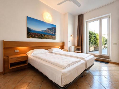 a bedroom with a large bed and a large window at Hotel Villa Clara in Nago-Torbole
