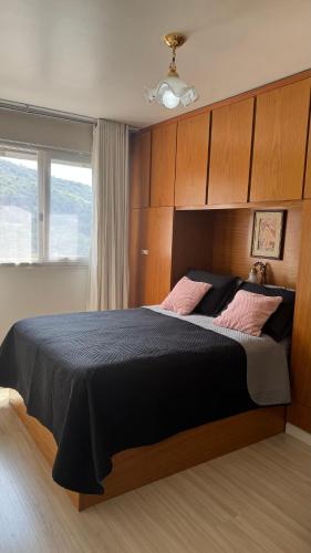 a bedroom with a large bed with black sheets and pink pillows at Ap Centro - Wi-fi, Piscina, com Vista da Praça in Águas de Lindoia