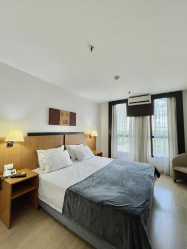 a bedroom with a large bed with a table and a couch at Flat 315 - Comfort Hotel Taguatinga - Particular in Brasília