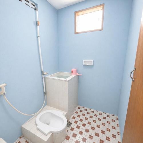 a blue bathroom with a toilet and a shower at Hotel Budi Famili Budget Syariah in Ciamis