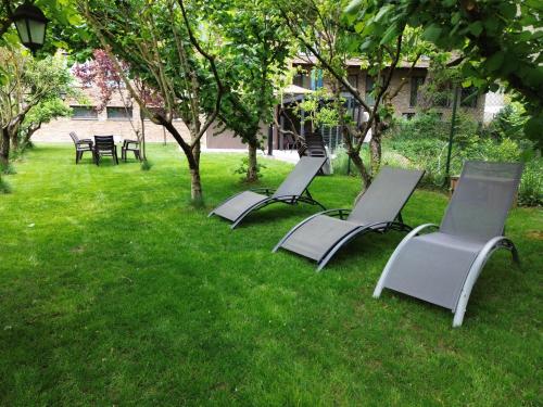 a group of chairs sitting in the grass at Apartamentos Ordesa Ainsa in Aínsa