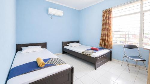 a bedroom with two beds and a chair and a window at Hotel Budi Famili Budget Syariah in Ciamis