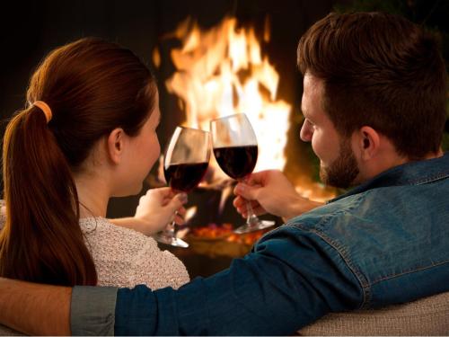 a man and woman drinking wine in front of a fire at The Woodbridge Tasmania in New Norfolk