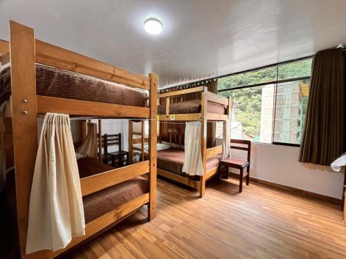a room with three bunk beds and a window at Nativus Hostel Machu Picchu in Machu Picchu