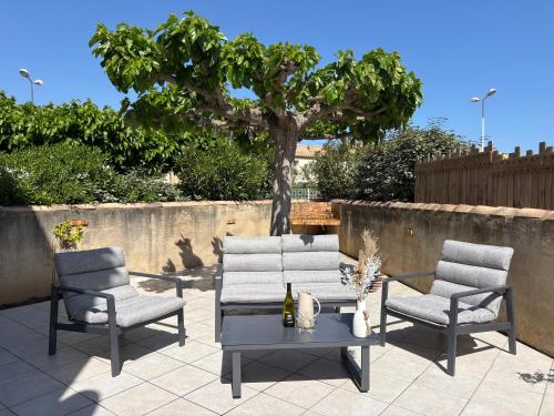 a patio with two chairs and a table and a tree at Escales du Sud, Frontignan Plage in Frontignan