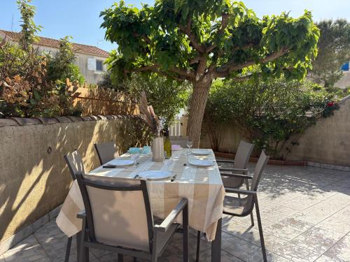 a table with chairs and a tree in a patio at Escales du Sud, Frontignan Plage in Frontignan