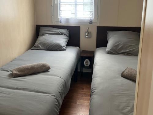 two twin beds in a room with a window at Camping le petit RIO in Noyelles-sur-Mer