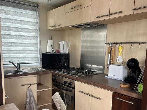 a kitchen with a sink and a stove top oven at Camping le petit RIO in Noyelles-sur-Mer