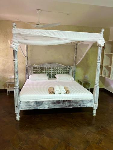 a bed with a canopy with two shoes on it at Studio Leliya in Malindi