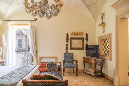 a bedroom with a bed and a chair and a chandelier at Palazzo Nobili in Capri