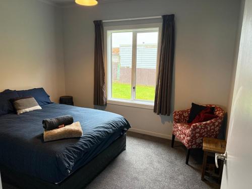 a bedroom with a bed and a window and a chair at Marvellous on Maggie in Invercargill
