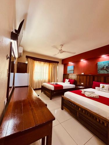 a hotel room with two beds with red walls at Caye Caulker Plaza Hotel in Caye Caulker