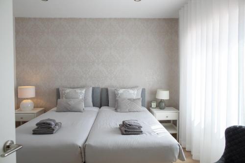 a bedroom with a large white bed with towels on it at Sun & Salt Villa in Alvor