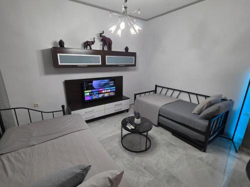 a living room with a couch and a tv at Rosemary Guesthouse in Kavála