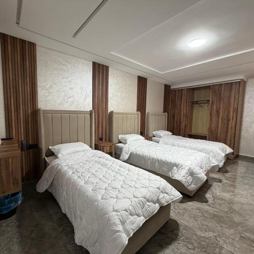 a hotel room with three beds with white sheets at Chambre Triple Séjour Confortable à Berkane in Berkane