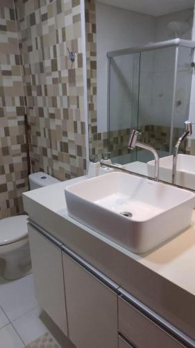 a bathroom with a white sink and a toilet at Apart Condomínio Jubiabá in Ilhéus
