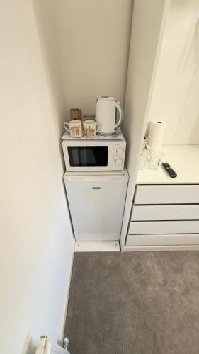 a small kitchen with a microwave on top of cabinets at Suite 2 En-suite Room with Double Bed in Edinburgh