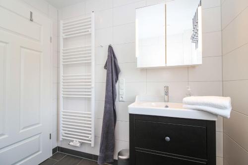 a white bathroom with a sink and a mirror at Kleine-Auszeit in Greetsiel