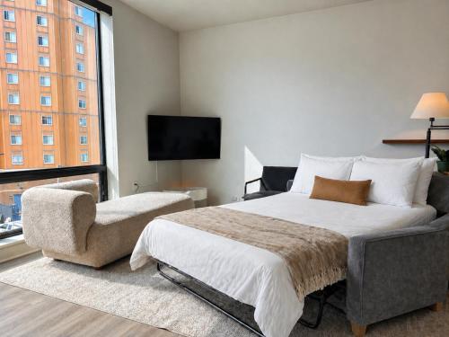 a bedroom with a bed and a chair and a television at East Side Luxury 1BR Apt - Near Brady St with Balcony and Lounge - Sleeps 4 in Milwaukee