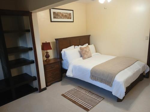 a bedroom with a bed and a night stand with a lamp at Yellow Leaf Suite in West End