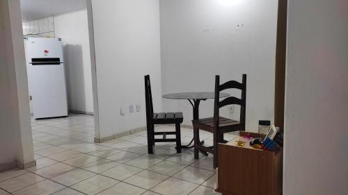 a kitchen with a table and two chairs and a refrigerator at Quarto em Casa Completa no Centro de Ilhéus in Ilhéus