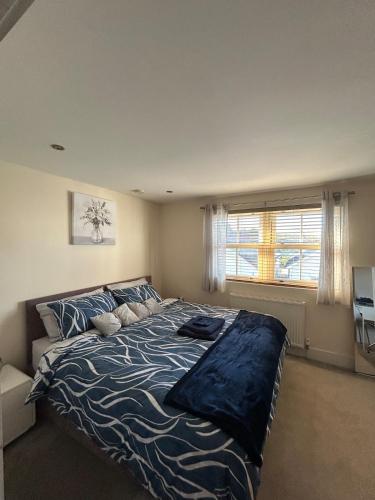 a bedroom with a bed with a blue comforter and a window at Comfort Horizon Egham in Egham