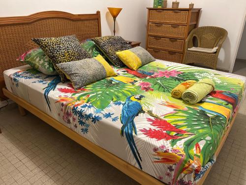 a bed with a colorful quilt with a parrot on it at Maison Petit Paradis in Basse-Terre