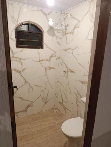 a bathroom with a toilet and a stone wall at Estância Serra Du Capiau 01 in Mairiporã