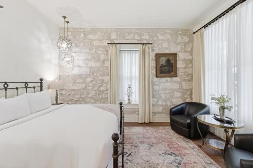 a bedroom with a bed and a chair and a table at Shopkeeper's Inn in Fredericksburg