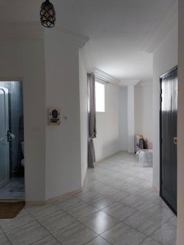 an empty room with white walls and a tile floor at Location saisonnière entre mer, forêt et calme in Raʼs al Jabal