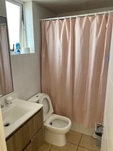 a bathroom with a toilet and a sink and a shower curtain at Oceanica Departamento in Iquique