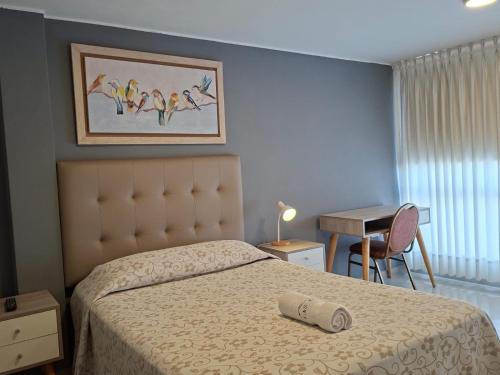 a bedroom with a bed and a table with a desk at Casa Las Flores Ica in Ica
