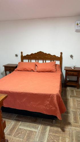 a bedroom with a bed with orange sheets and two tables at BRISAN descanso sol,y playa in Barra del Chuy