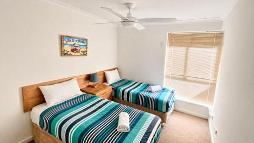 two beds in a small room with a window at Escape to 39 at Cape View in Busselton
