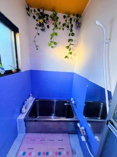 a bath tub in a blue bathroom with flowers on the wall at Horomisou in Noboribetsu